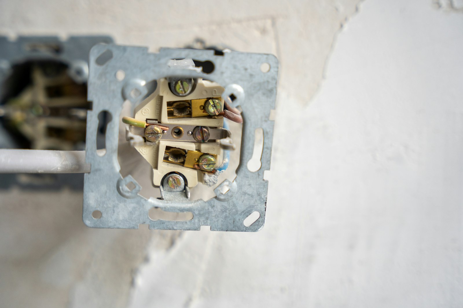 A wall socket opened up to show its wiring